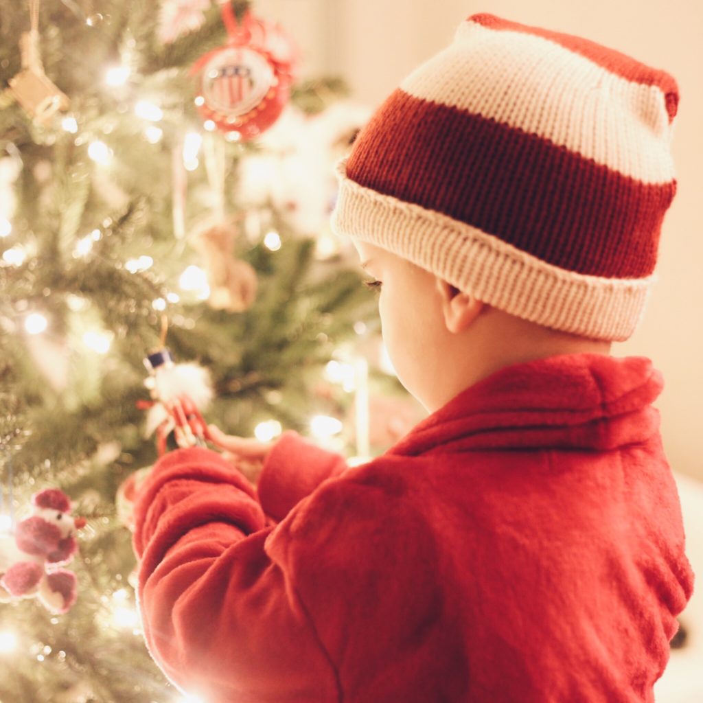 child decorating christmas tree in santa hat