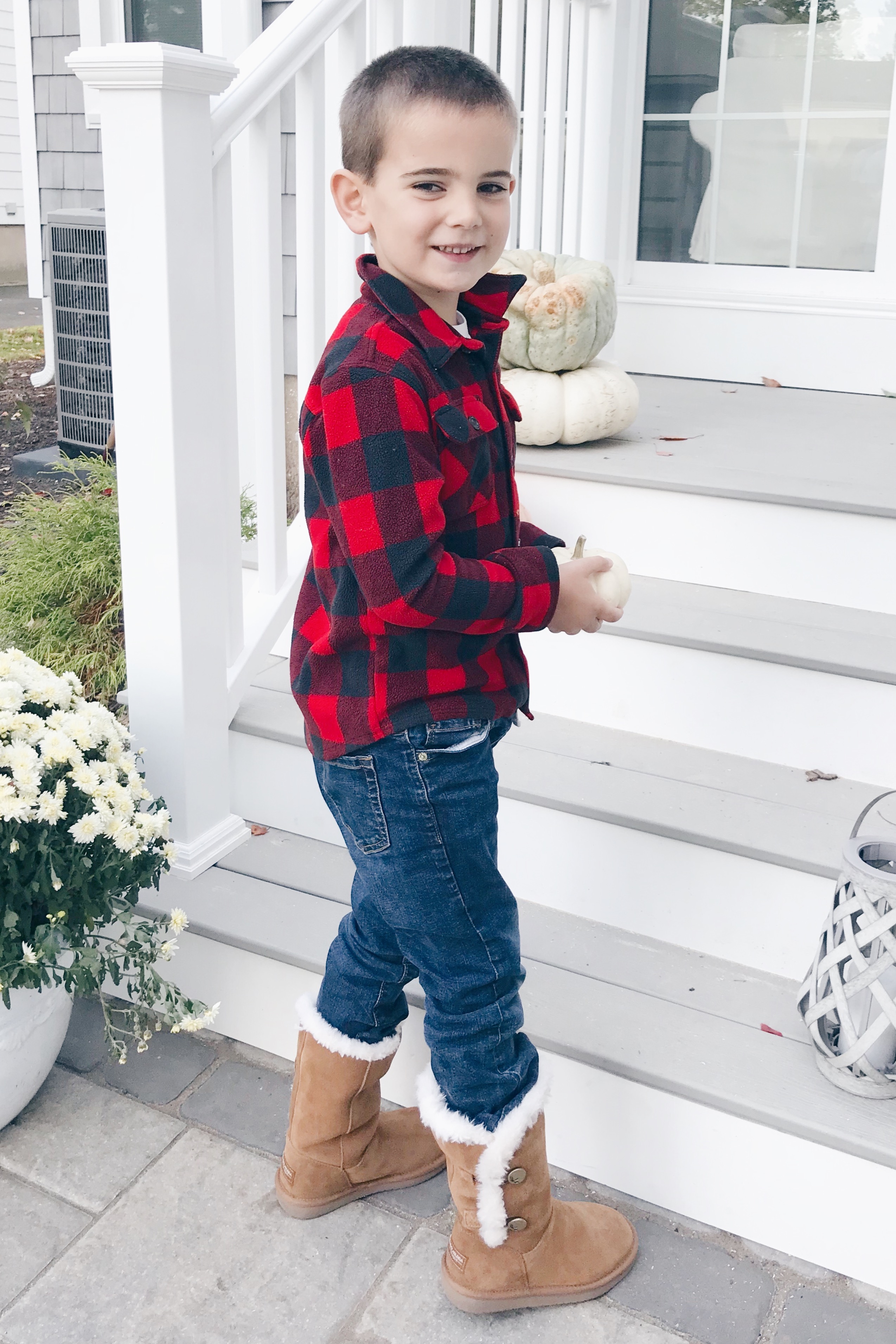 preschool boy decorating fall porch wearing kollaburra boots