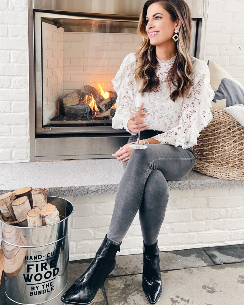 cute holiday outfit ideas - white lace ruffle sleeve top with black jeans and booties