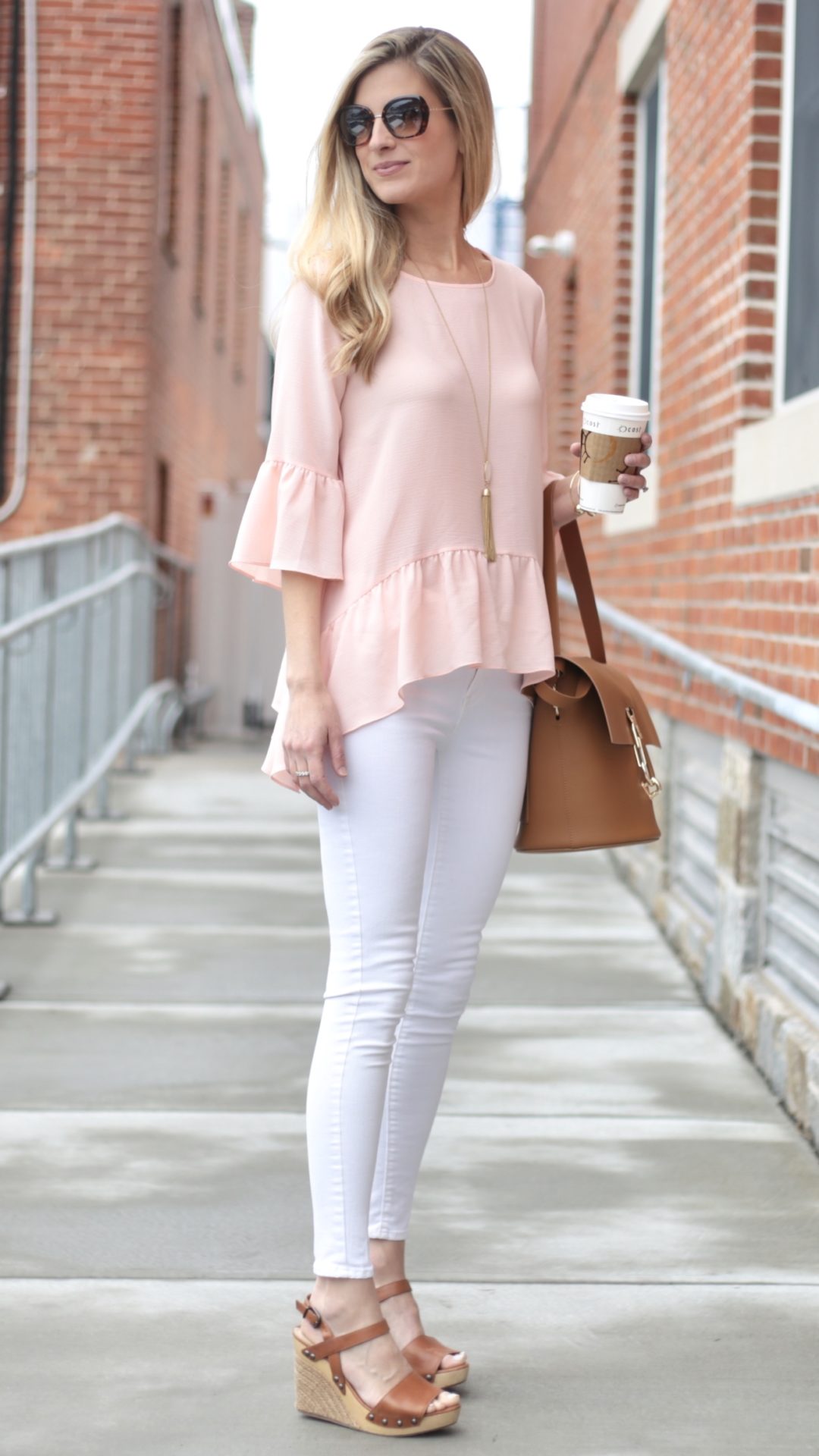 spring outfit ideas: pink ruffle hem top with white skinny jeans and wedge sandals