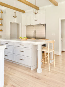 side by side full bridge and full freezer in modern white and gray kitchen with wood beams