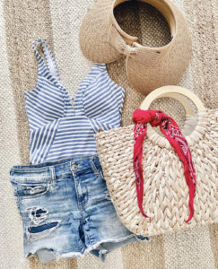 Walmart blue stripe one piece swimsuit with American Eagle midi shorts sleeve society straw bag and woven visor flat lay summer beach outfit