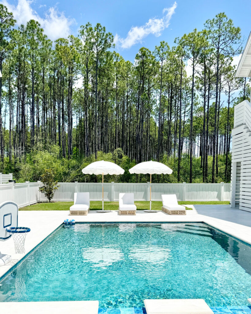 resort style pool with lounge chaise and outdoor fringe umbrellas