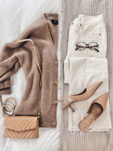 Polished business casual outfit for women over 40 with an oversized camel cardigan, white jeans, tortoiseshell glasses, nude quilted crossbody bag, and woven slingback heels.