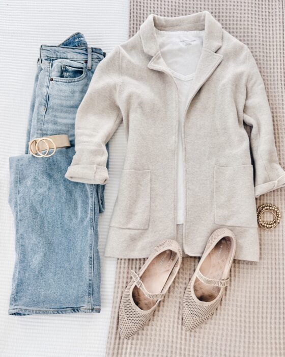 Effortlessly chic business casual outfit for women over 40 with light-wash denim, an oatmeal wool coat, white tee, nude Mary Jane flats, and a neutral belt.