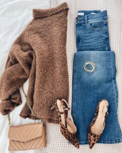 Trendy fall outfit for women over 40 featuring a cozy brown turtleneck sweater, dark-wash denim, nude quilted handbag, and statement leopard print slingback heels.