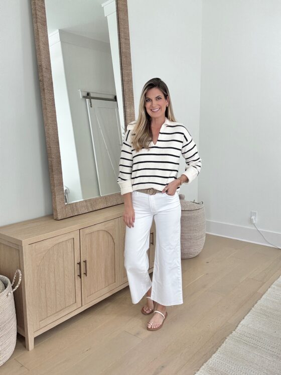 Classic spring outfit featuring white wide-leg cropped jeans, a striped pullover sweater, and minimalist sandals. A timeless neutral look for effortless style in 2025.