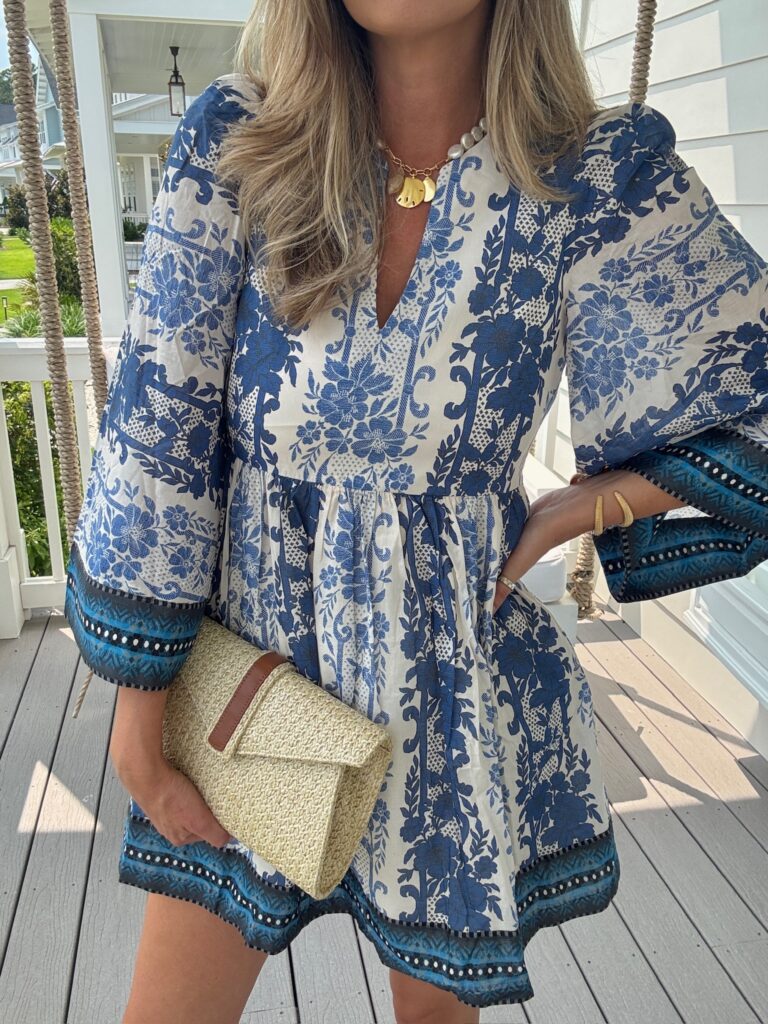 Blue and white floral print mini summer dress from Tuckernuck with bell sleeves and straw clutch